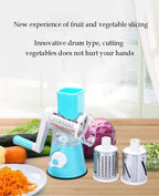 Blue manual rotary vegetable slicer and grater with interchangeable drums and sliced carrots.